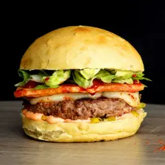 Un généreux burger savoyard avec un steak juteux, fromage fondant, légumes frais et une touche de piment sur un pain brioché.